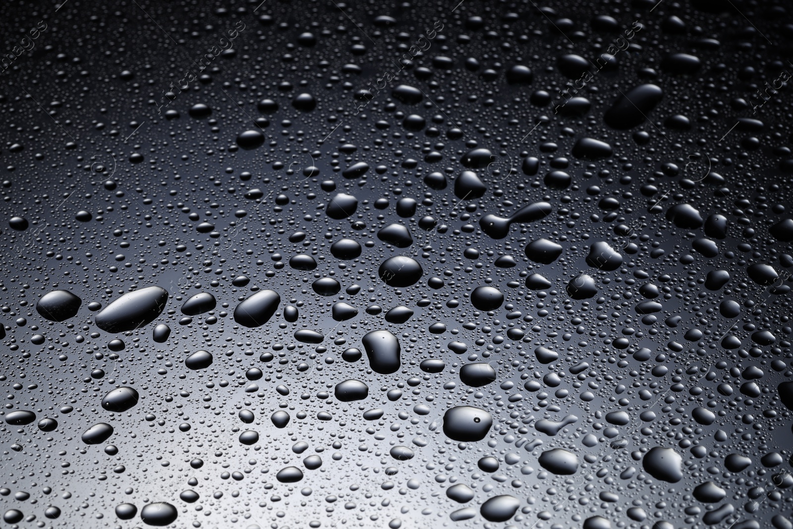 Photo of Water drops on dark glass surface, closeup