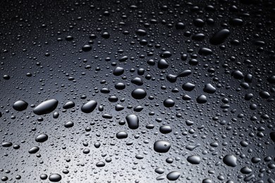 Photo of Water drops on dark glass surface, closeup