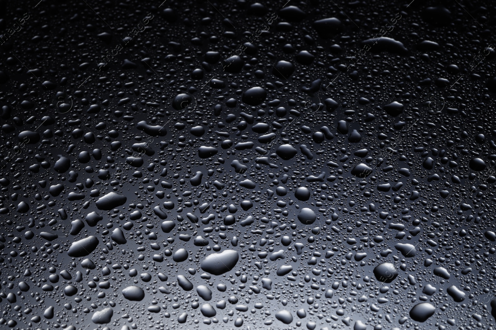 Photo of Water drops on dark glass surface, closeup