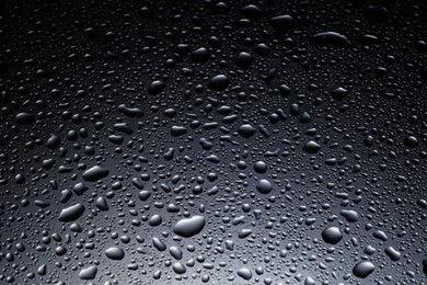 Water drops on dark glass surface, closeup