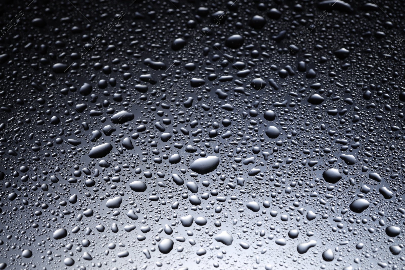 Photo of Water drops on dark glass surface, closeup