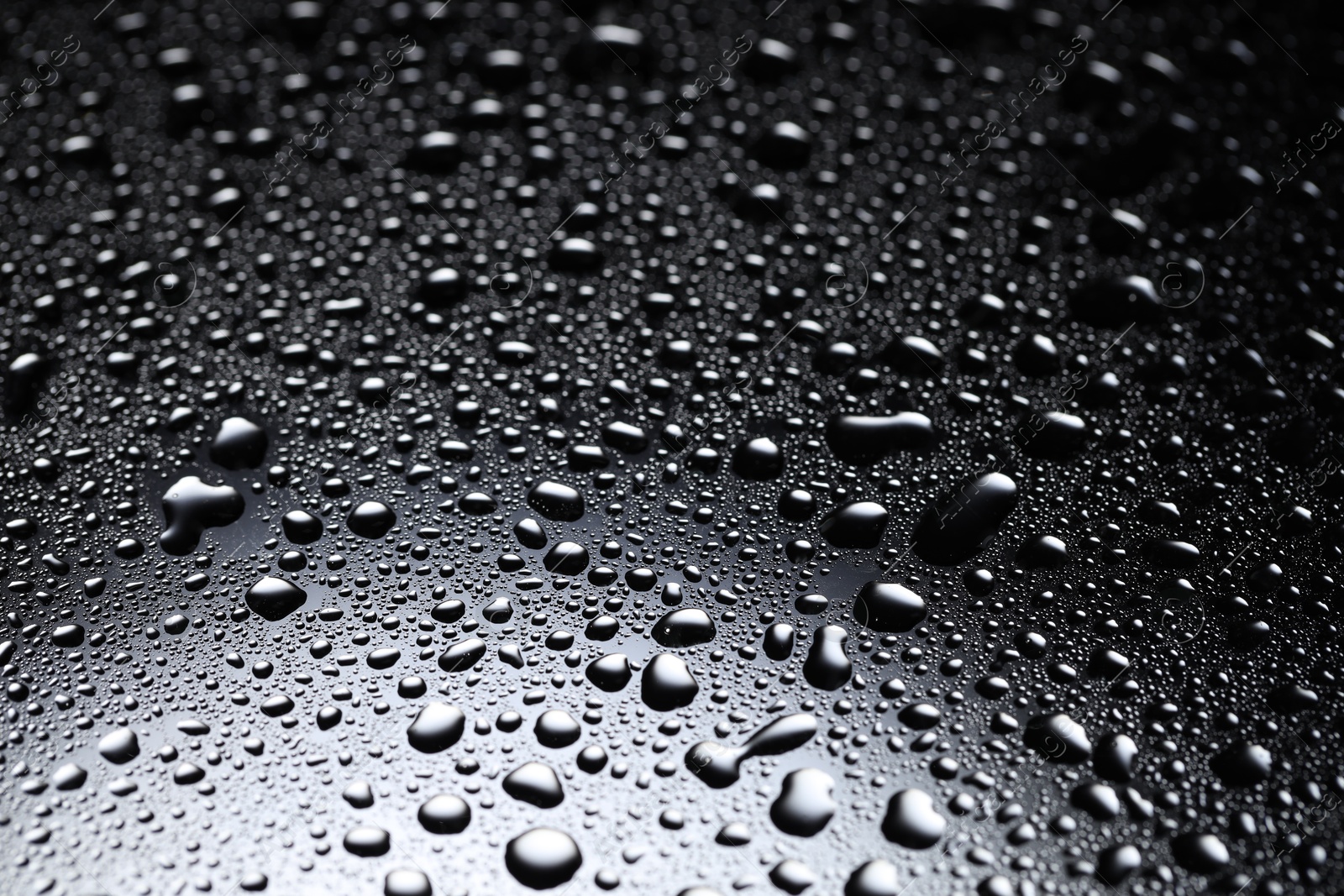 Photo of Water drops on dark glass surface, closeup