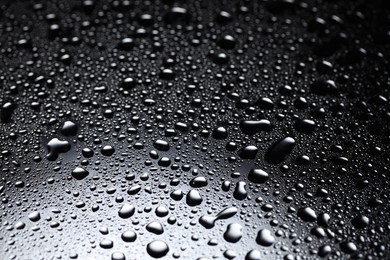 Photo of Water drops on dark glass surface, closeup