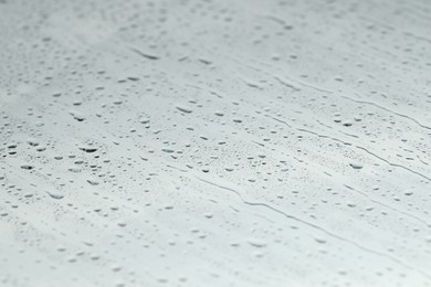 Photo of Water drops on light glass surface, closeup