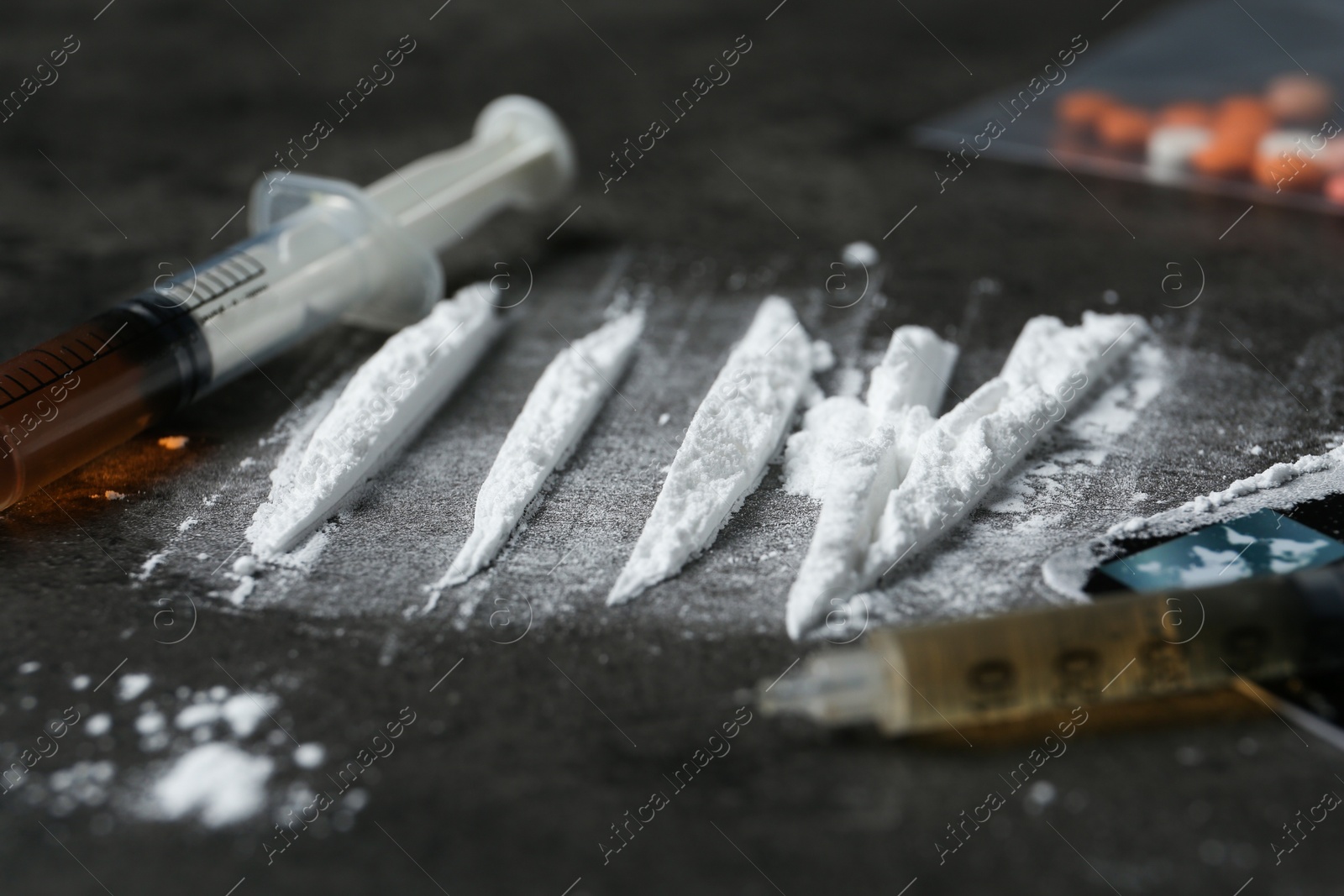 Photo of Drug addiction. Powder, syringes and credit card on gray textured table, closeup