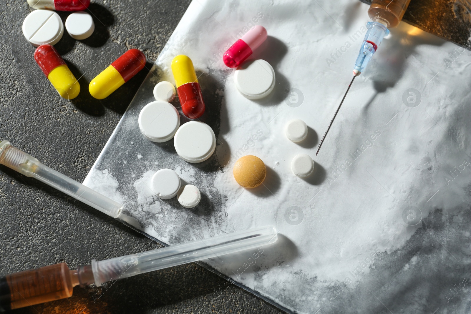 Photo of Drug addiction. Plastic bag with powder, syringes and pills on gray textured table, flat lay