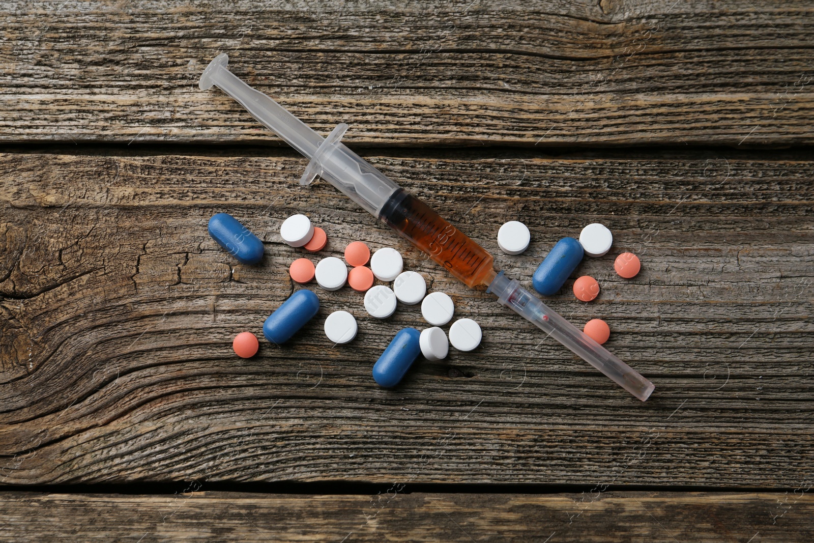 Photo of Drug addiction. Syringe and pills on wooden table, flat lay