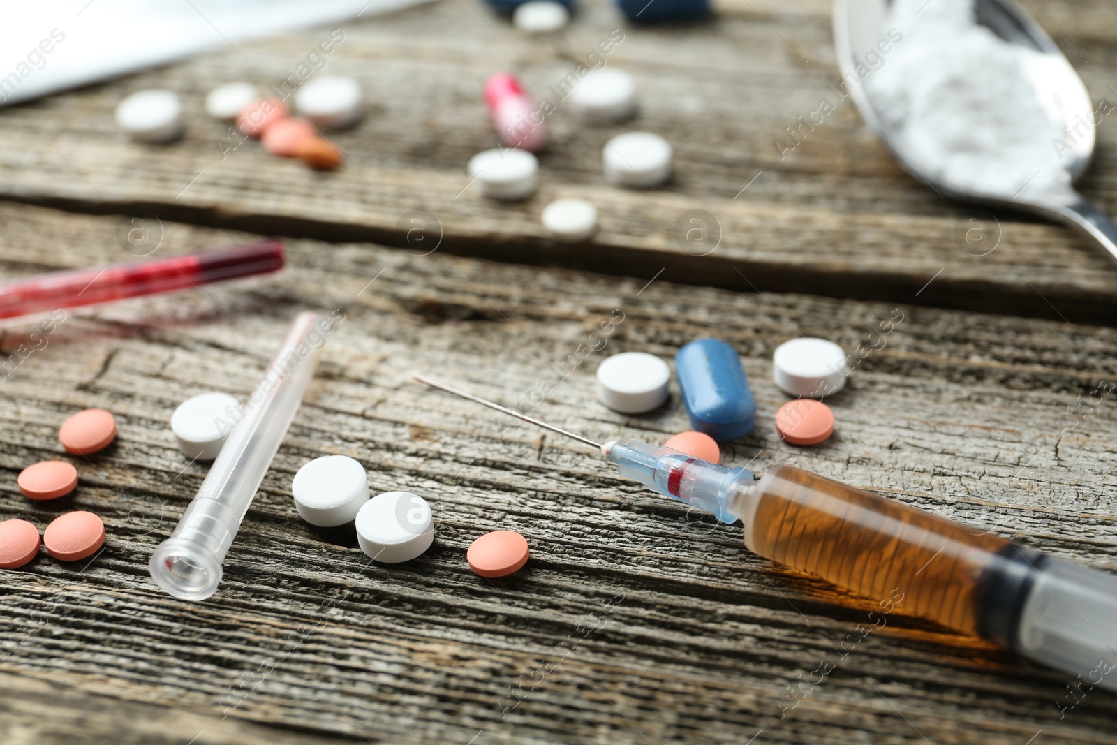 Photo of Drug addiction. Syringe and pills on wooden table, closeup