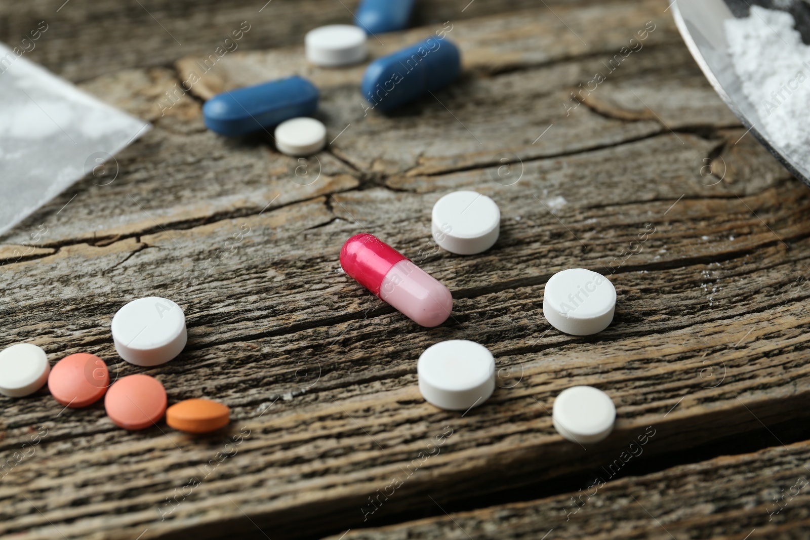 Photo of Drug addiction. Different pills on wooden table, closeup