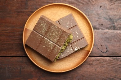 Photo of Pieces of tasty Dubai chocolate with pistachios and knafeh on wooden table, top view