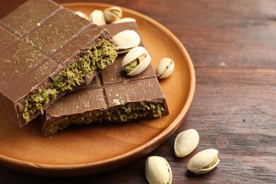 Photo of Pieces of tasty Dubai chocolate with pistachios and knafeh on wooden table, closeup