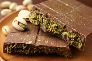 Photo of Pieces of tasty Dubai chocolate bar with pistachios and knafeh on table, closeup