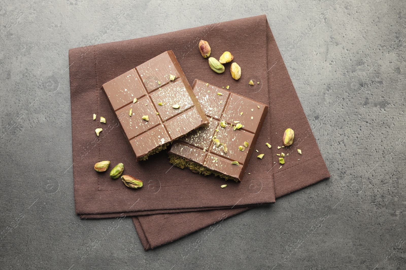 Photo of Pieces of tasty Dubai chocolate with pistachios and knafeh on grey table, top view