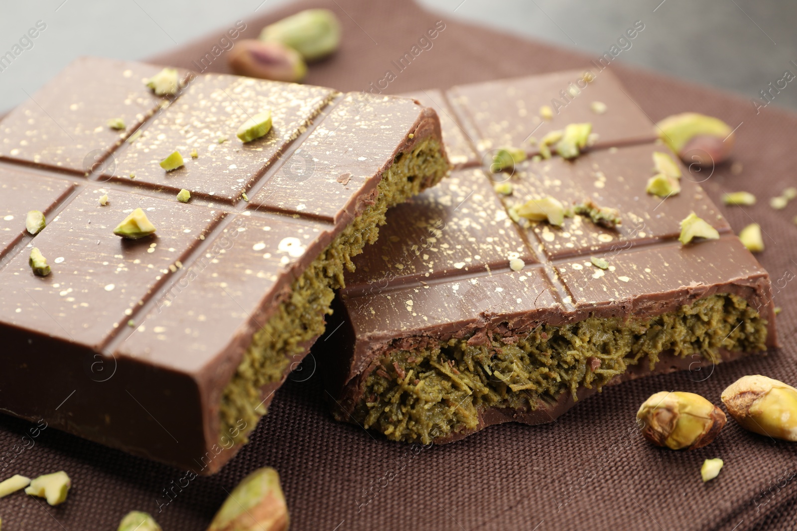 Photo of Pieces of tasty Dubai chocolate bar with pistachios and knafeh on table, closeup