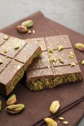 Photo of Pieces of tasty Dubai chocolate with pistachios and knafeh on grey table, closeup