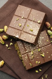 Photo of Pieces of tasty Dubai chocolate with pistachios and knafeh on grey table, top view