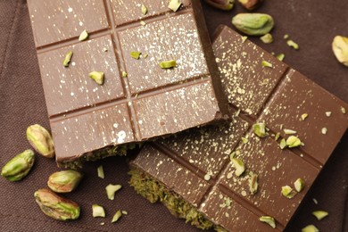 Photo of Pieces of tasty Dubai chocolate with pistachios and knafeh on napkin, top view