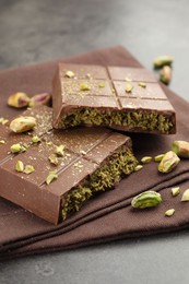 Photo of Pieces of tasty Dubai chocolate with pistachios and knafeh on grey table, closeup