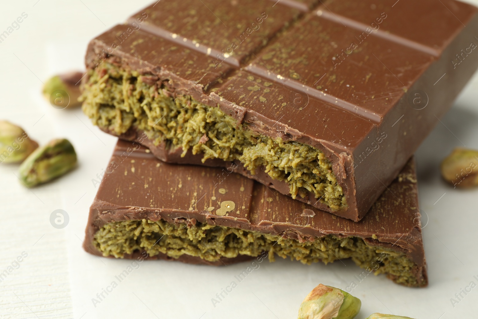 Photo of Pieces of tasty Dubai chocolate with pistachios and knafeh on white wooden table, closeup