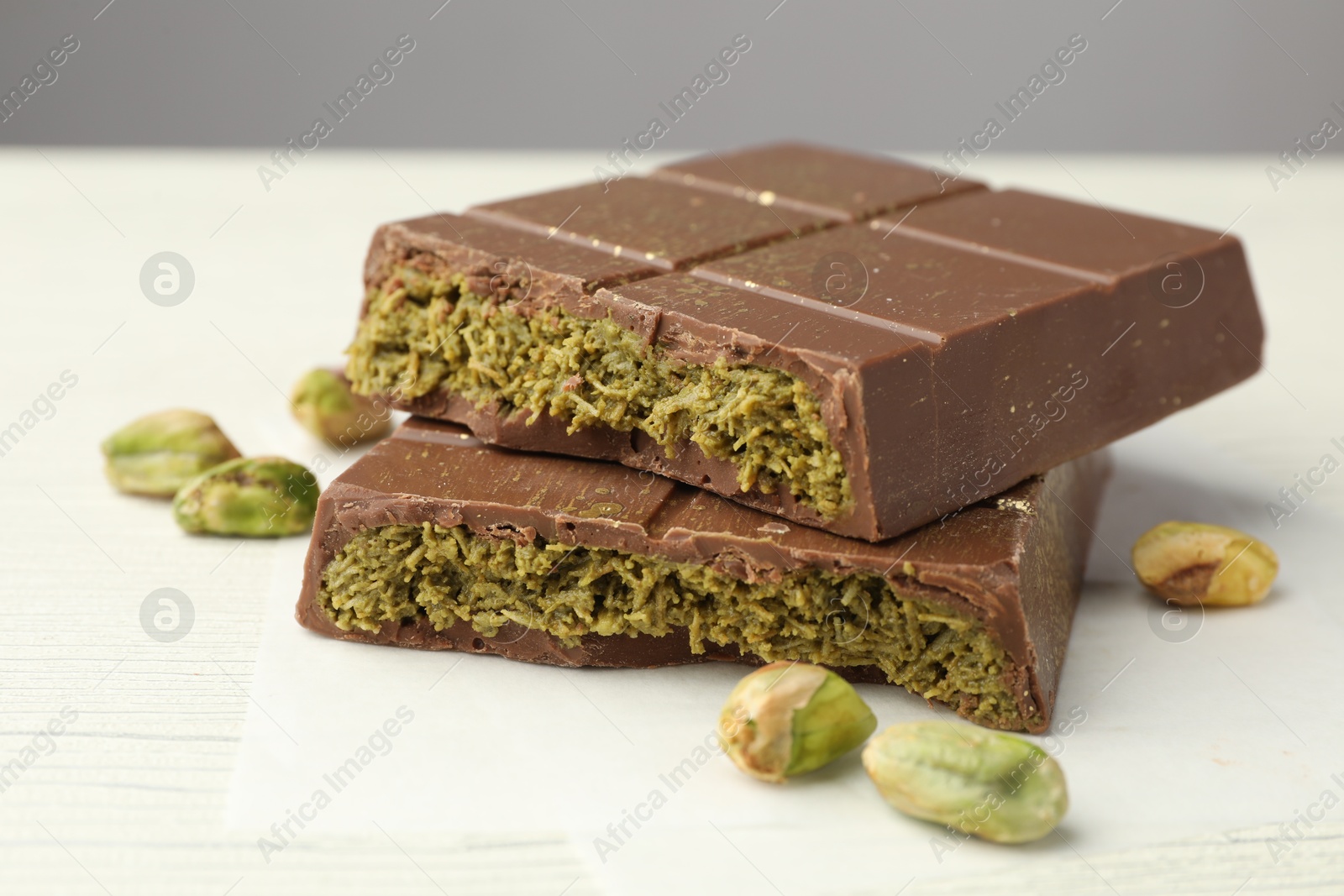 Photo of Pieces of tasty Dubai chocolate with pistachios and knafeh on white wooden table, closeup