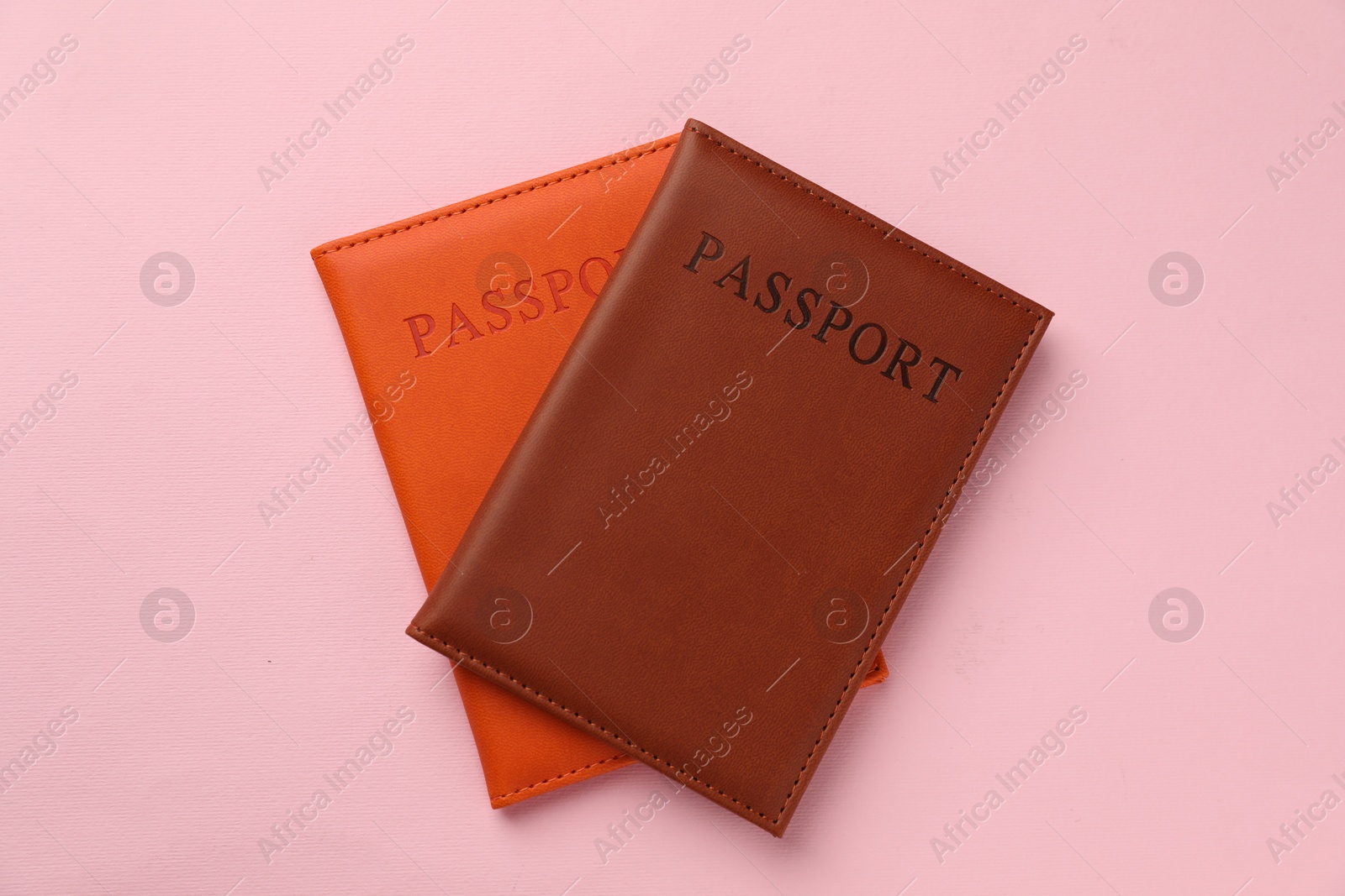 Photo of Passports in color covers on pink background, top view