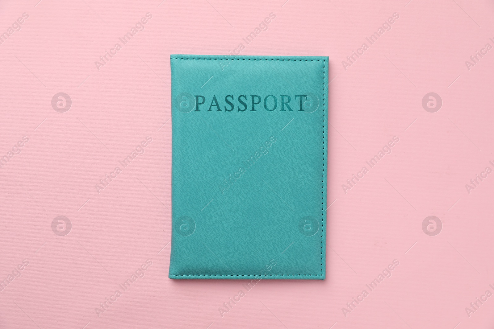 Photo of Passport in light blue cover on pink background, top view