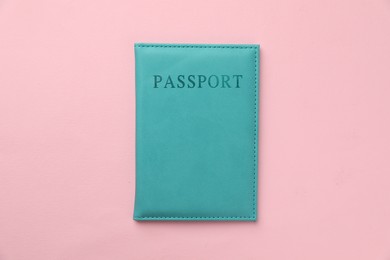 Photo of Passport in light blue cover on pink background, top view