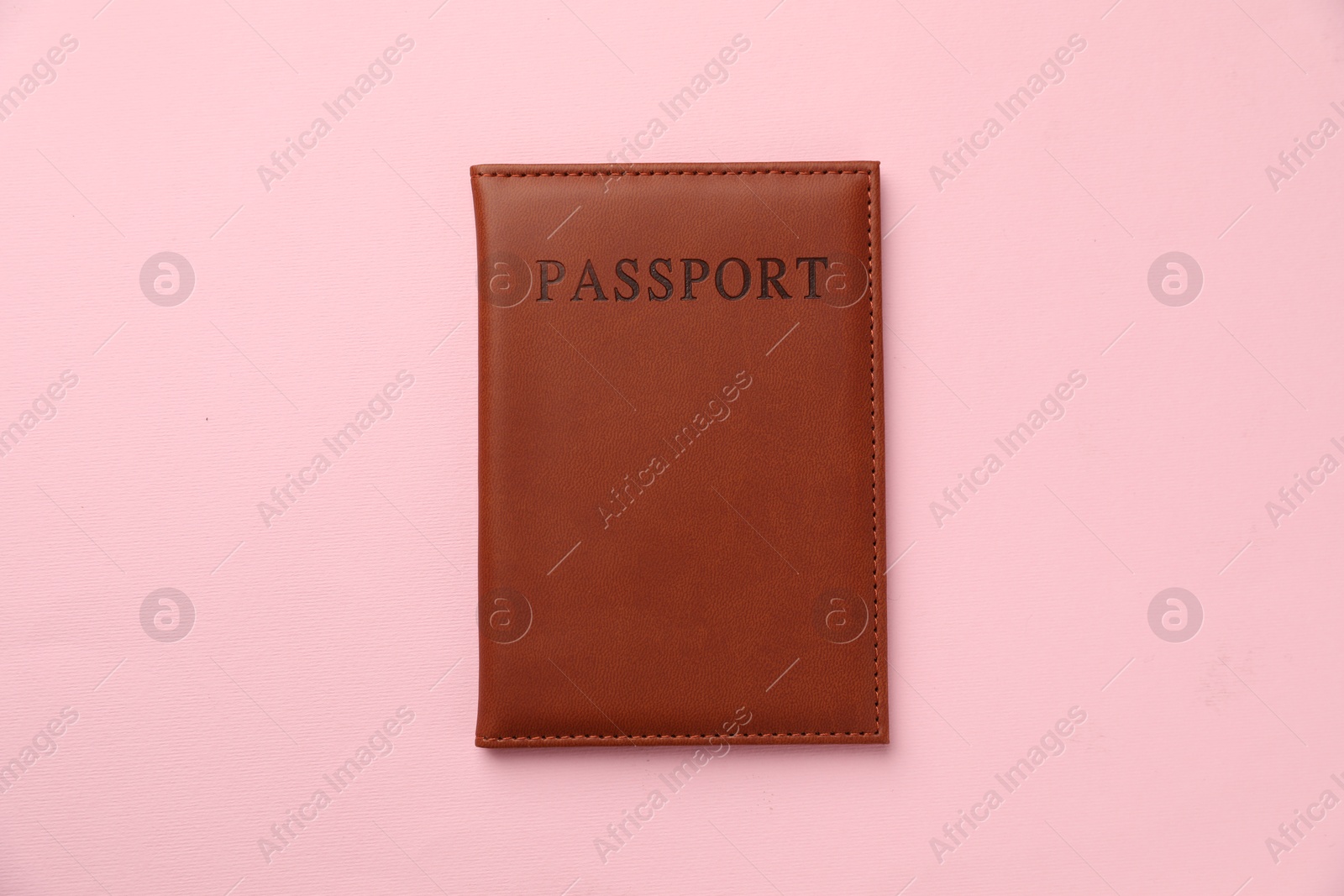 Photo of Passport in brown cover on pink background, top view