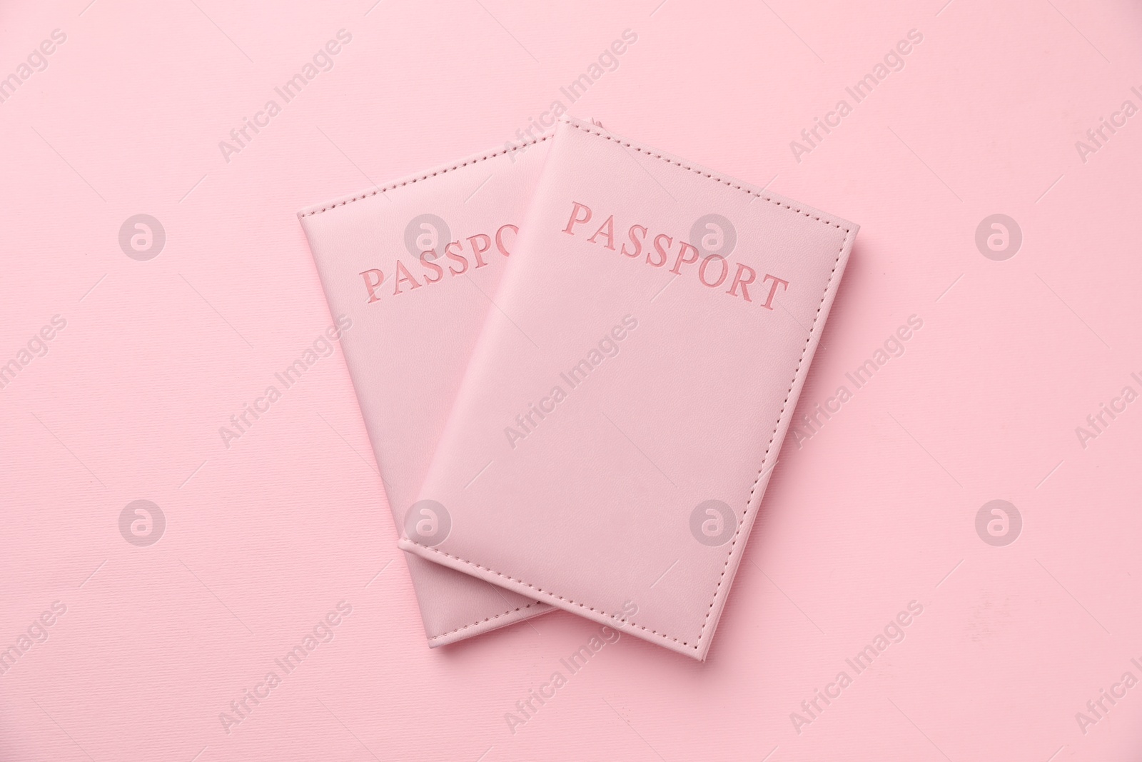 Photo of Passports in color covers on pink background, top view