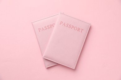 Photo of Passports in color covers on pink background, top view