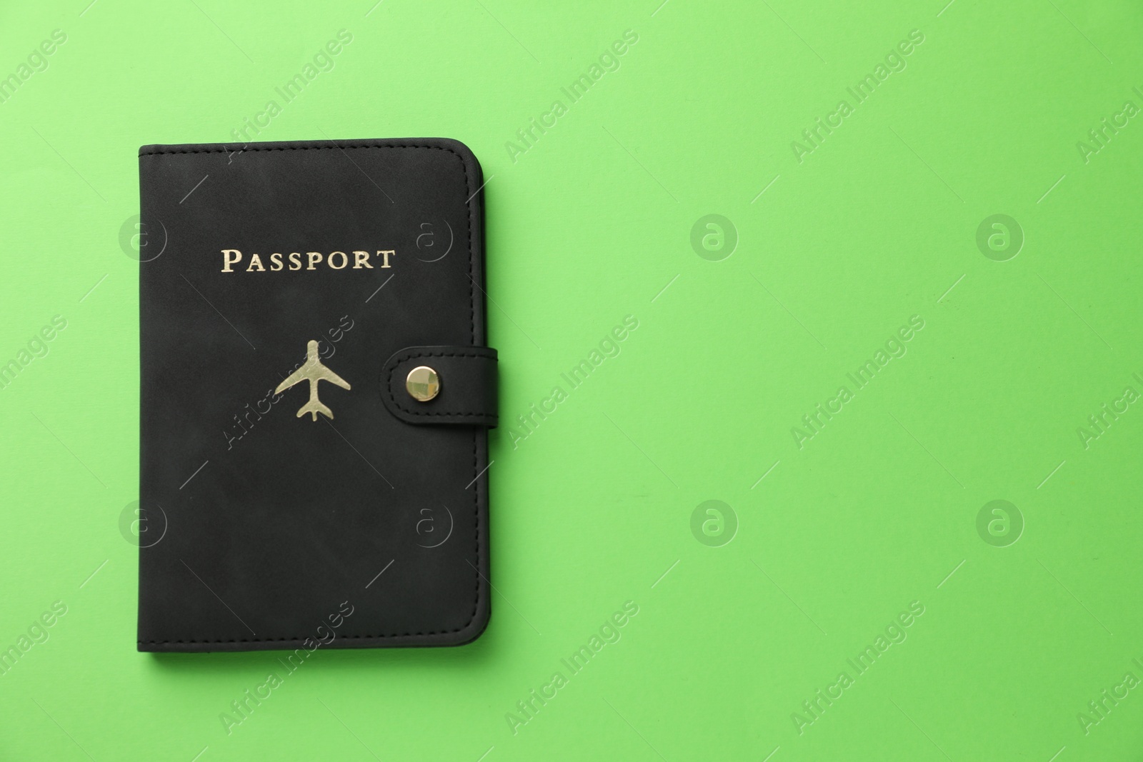 Photo of Passport in black cover on green background, top view. Space for text