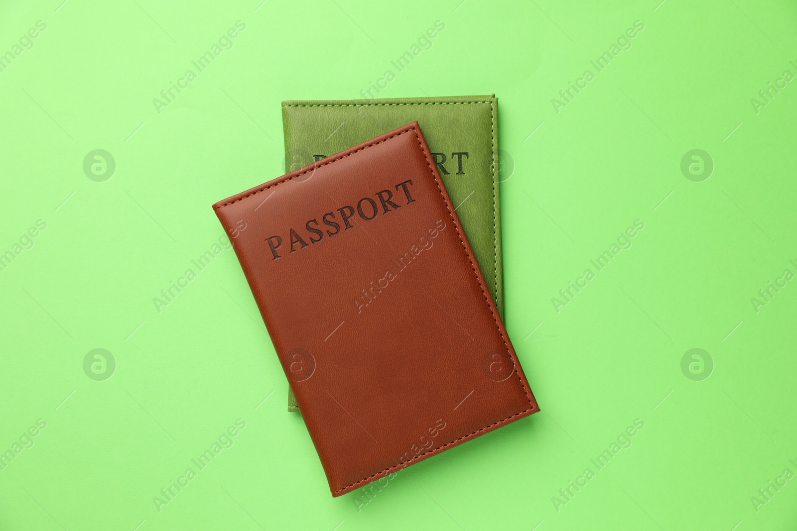 Photo of Passports in color covers on green background, top view