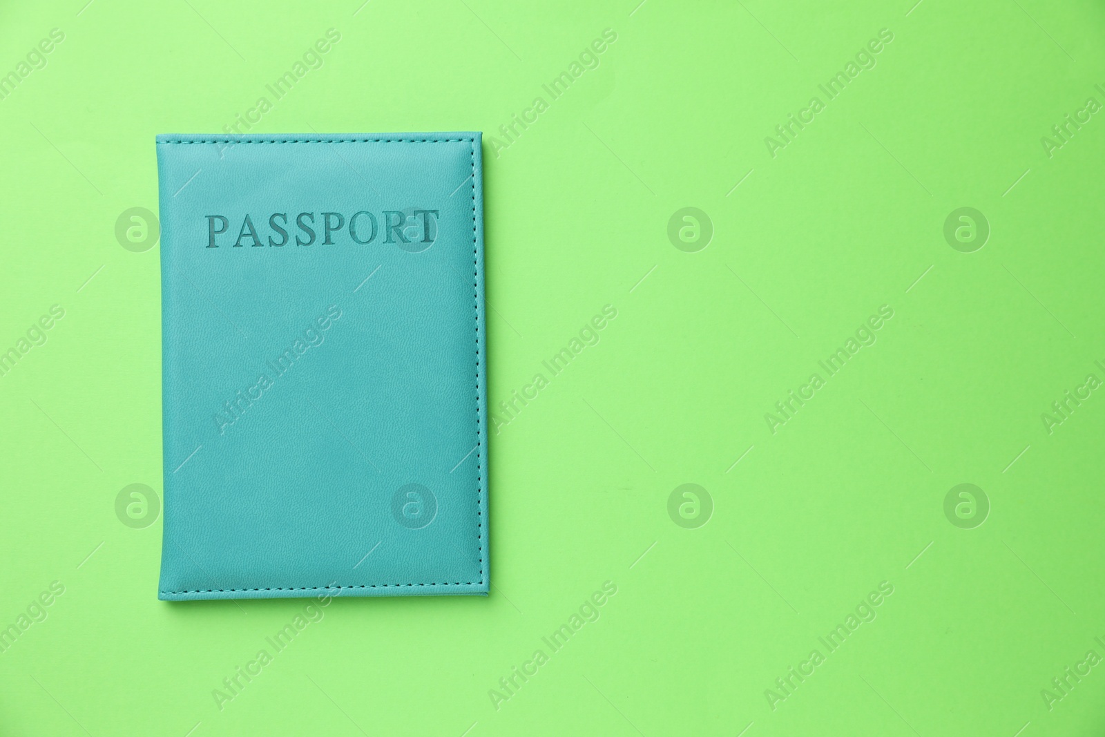 Photo of Passport in light blue cover on green background, top view. Space for text