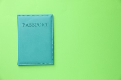 Photo of Passport in light blue cover on green background, top view. Space for text