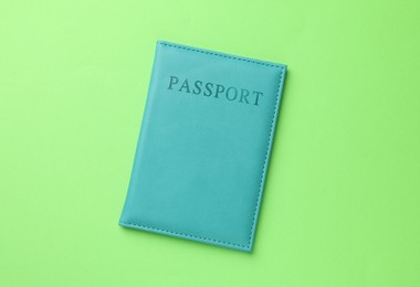 Photo of Passport in light blue cover on green background, top view