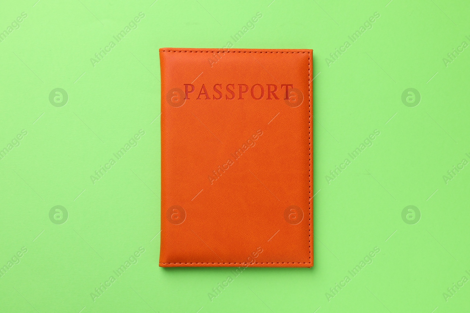 Photo of Passport in orange cover on green background, top view