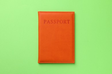 Photo of Passport in orange cover on green background, top view