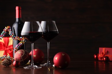 Photo of Red wine and beautiful Christmas decor on wooden table. Space for text