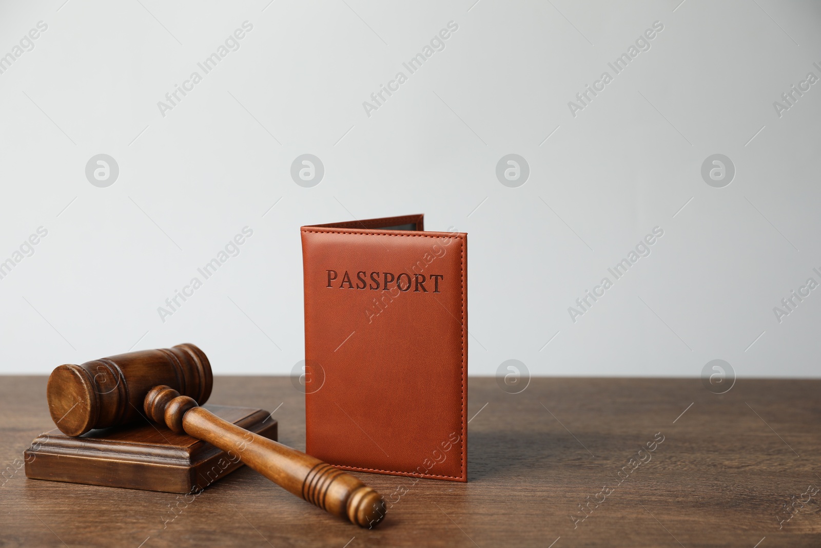 Photo of Passport in brown cover and judge's gavel on wooden table, space for text