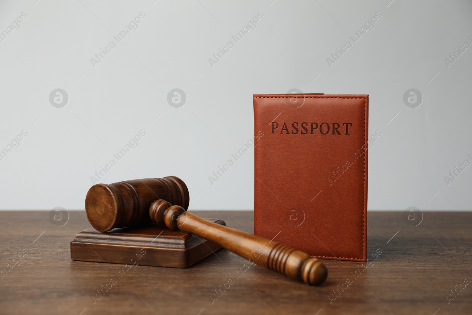 Photo of Passport in brown cover and judge's gavel on wooden table