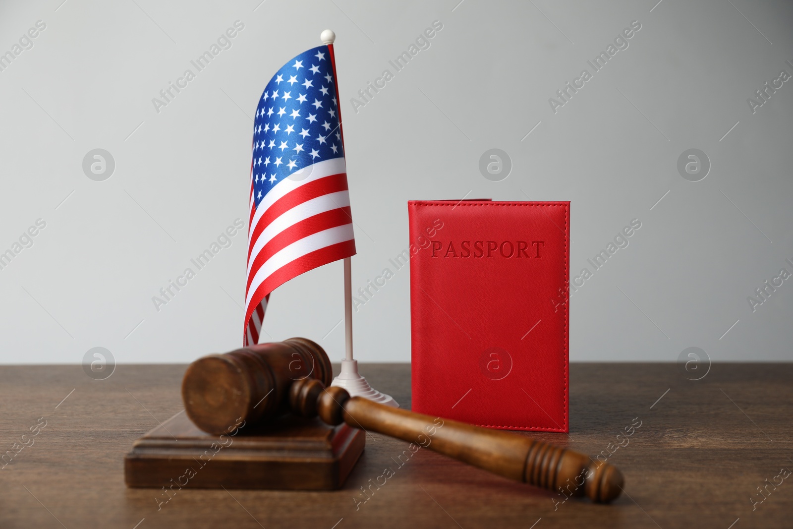 Photo of Passport in red cover, gavel and flag of United States on wooden table