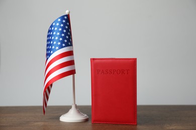 Photo of Passport in red cover and flag of United States on wooden table