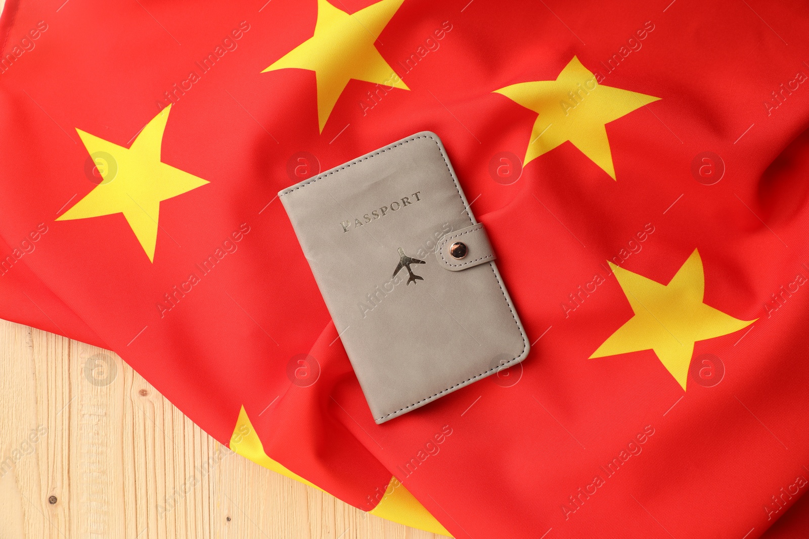 Photo of Passport in leather cover and flag of China on wooden table, top view