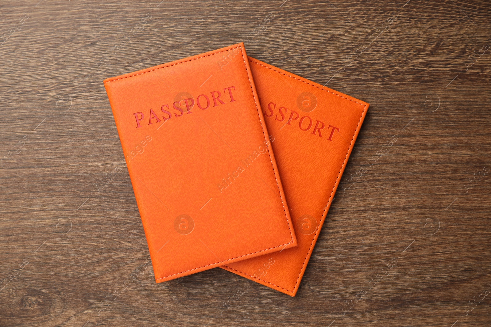 Photo of Passports in orange covers on wooden table, top view