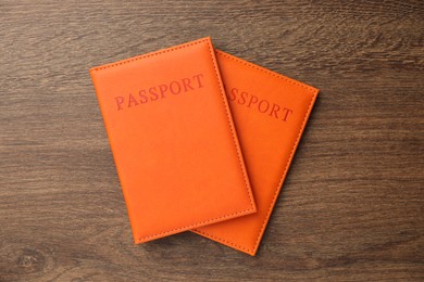 Photo of Passports in orange covers on wooden table, top view