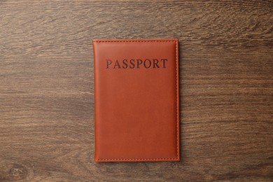 Photo of Passport in brown cover on wooden table, top view