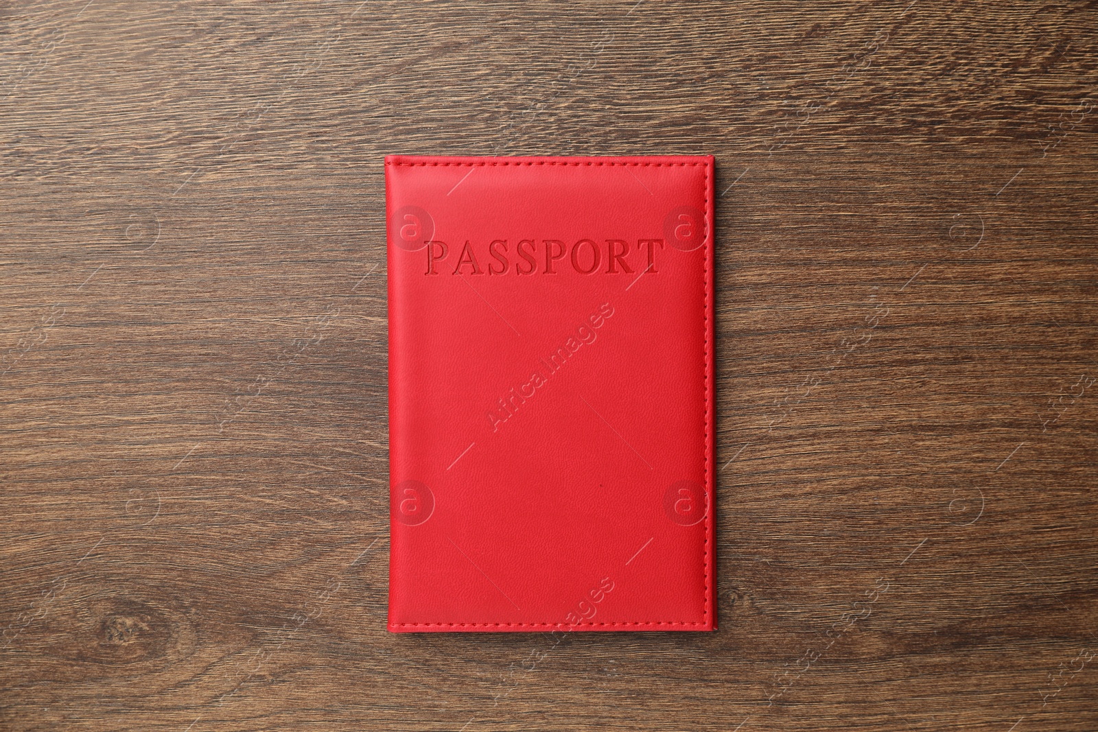 Photo of Passport in red cover on wooden table, top view