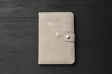 Photo of Passport in leather cover on black wooden table, top view