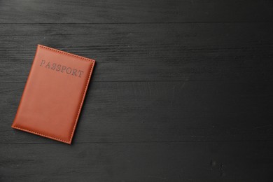 Photo of Passport in brown cover on black wooden table, top view. Space for text