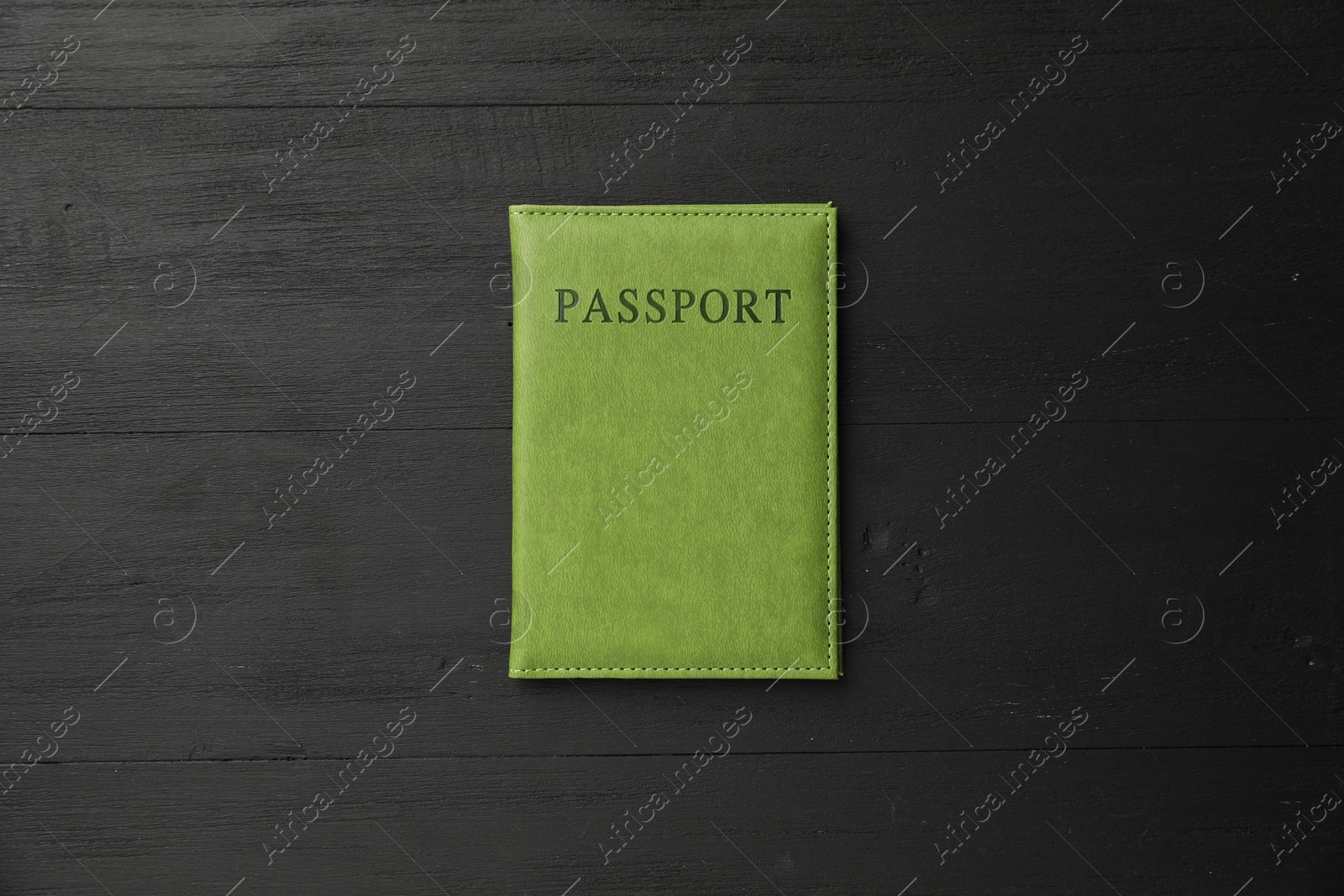 Photo of Passport in green cover on black wooden table, top view